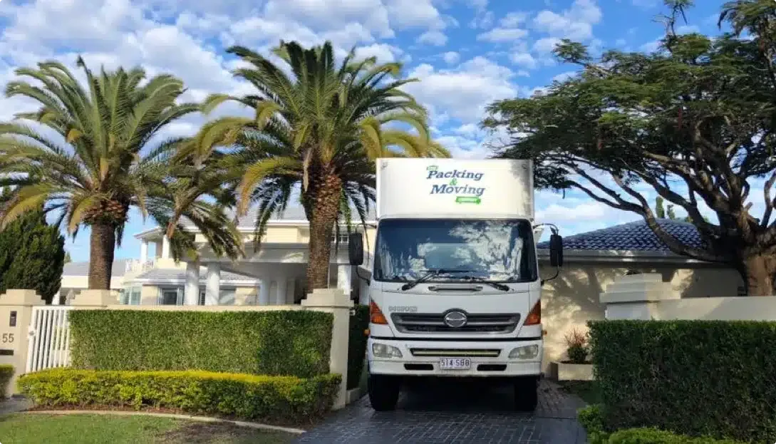 Moving Truck Parked in a Driveway With Palm Trees — The Packing & Moving Company in Tanah Merah, QLD